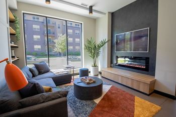 A living room with a grey couch, a coffee table, a television, and a large window.